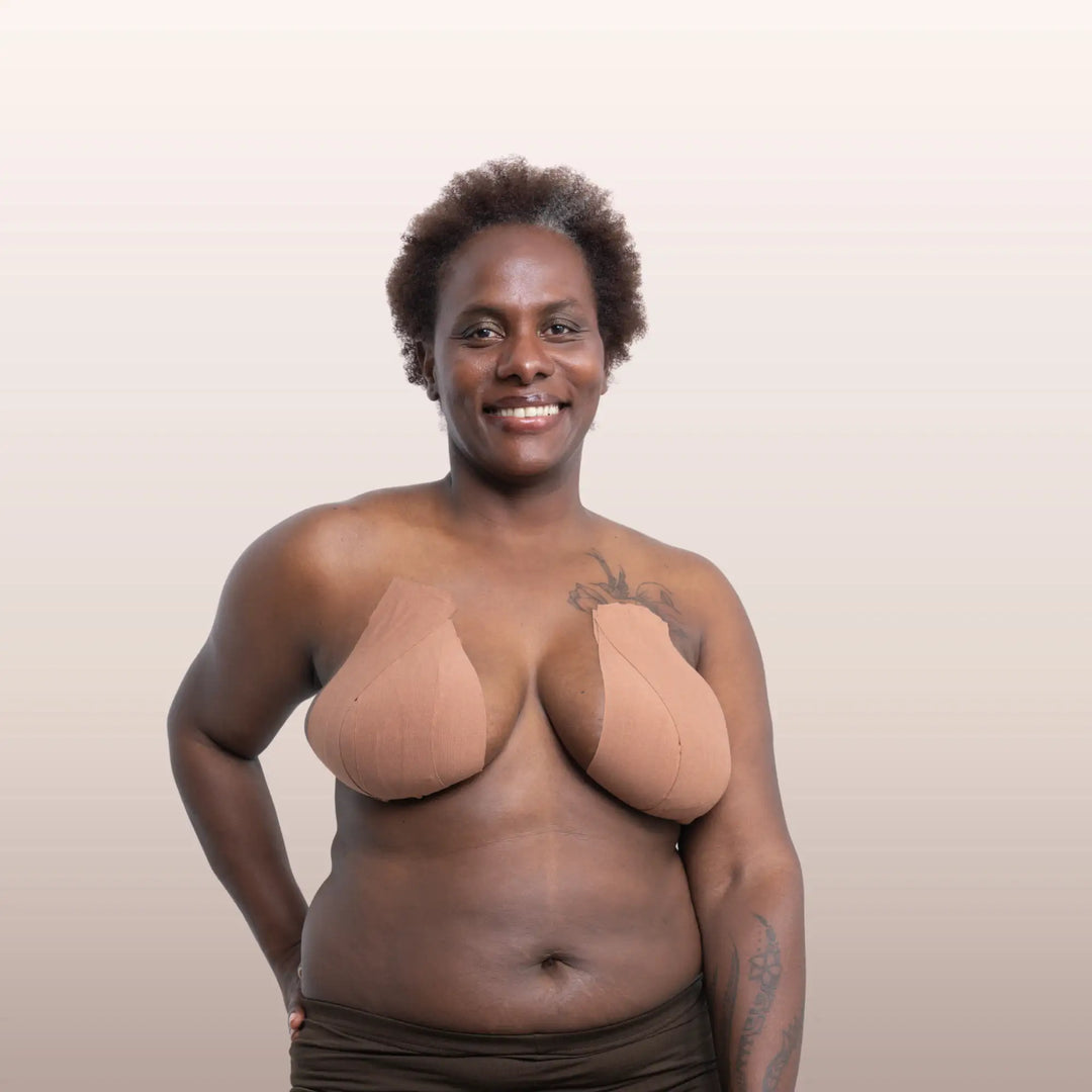 Gros plan sur une femme noire ayant correctement positionné la bande adhésive marron La Bande à Lolo pour un maintien naturel de la poitrine.