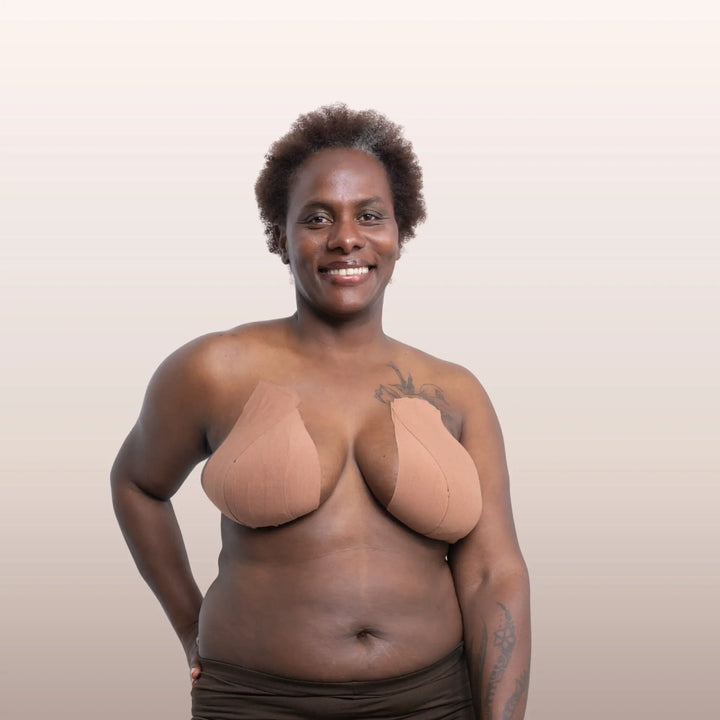 Gros plan sur une femme noire ayant correctement positionné la bande adhésive marron La Bande à Lolo pour un maintien naturel de la poitrine.
